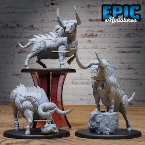 May include: Three gray, detailed, miniature bull sculptures. The bull on the left is charging, the bull in the center is standing, and the bull on the right is standing with its head lowered. The bulls are all made of a textured material and have horns.