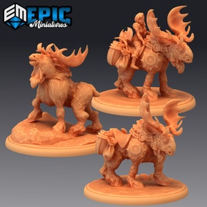 May include: Three miniature figurines of moose with riders. The moose are brown and have antlers. The riders are wearing fantasy-style clothing. The figurines are on circular bases.