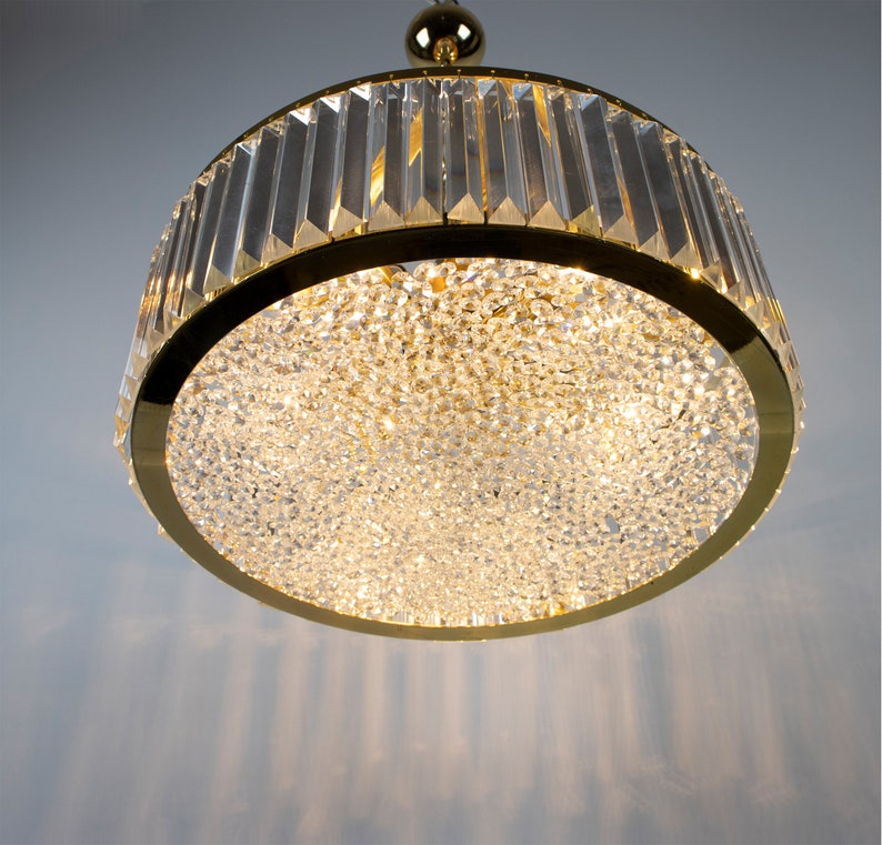 Pu&ograve; includere: Un lampadario rotondo in cristallo dorato. Il lampadario ha un design moderno ed &egrave; perfetto per aggiungere un tocco di eleganza a qualsiasi stanza.