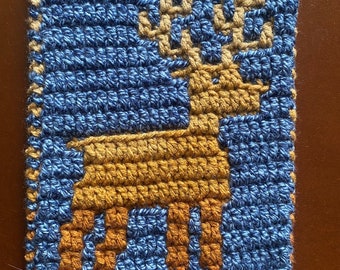 May include: A blue and brown crocheted square with a deer design. The deer is brown and has antlers.
