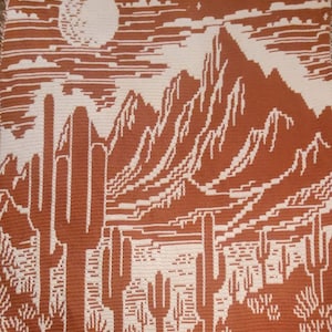 Peut inclure: Une couverture au crochet avec un motif de paysage d&eacute;sertique. La couverture repr&eacute;sente une cha&icirc;ne de montagnes, des cactus et une pleine lune dans un ciel &eacute;toil&eacute;. Les couleurs sont le brun et le blanc.
