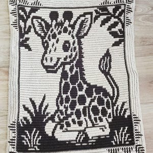 May include: A crocheted square with a black and white giraffe design. The giraffe has a spotted pattern and is surrounded by stylized grass and foliage. The border features a detailed, geometric pattern.