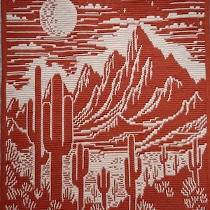 Peut inclure: Une tapisserie murale en crochet rouge et blanc repr&eacute;sentant un paysage d&eacute;sertique avec des montagnes, une pleine lune et des cactus.