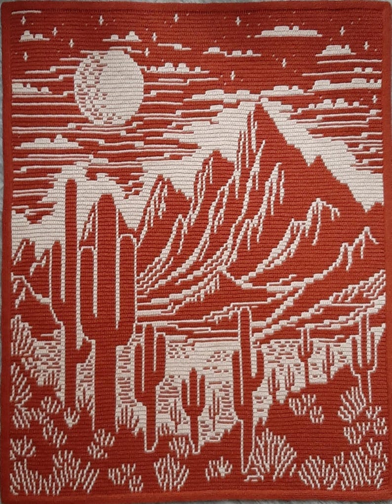 Peut inclure: Une tapisserie murale en crochet rouge et blanc repr&eacute;sentant un paysage d&eacute;sertique avec des montagnes, une pleine lune et des cactus.