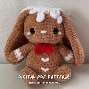 May include: A crocheted gingerbread bunny amigurumi toy with white icing details, red bow, and brown fur. The toy is sitting on a white surface. The text "DIGITAL PDF PATTERN!! @CUTEELITTLECREATIONS" is visible below the toy.