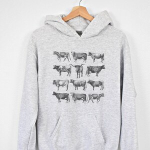 May include: A gray hooded sweatshirt with a print of various black and white cow illustrations.