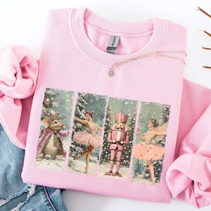 Puede incluir: Sudadera rosa con un estampado de estilo vintage de un ratón, una bailarina, un cascanueces y un hada. La impresión es de estilo collage con cada personaje en un marco separado.