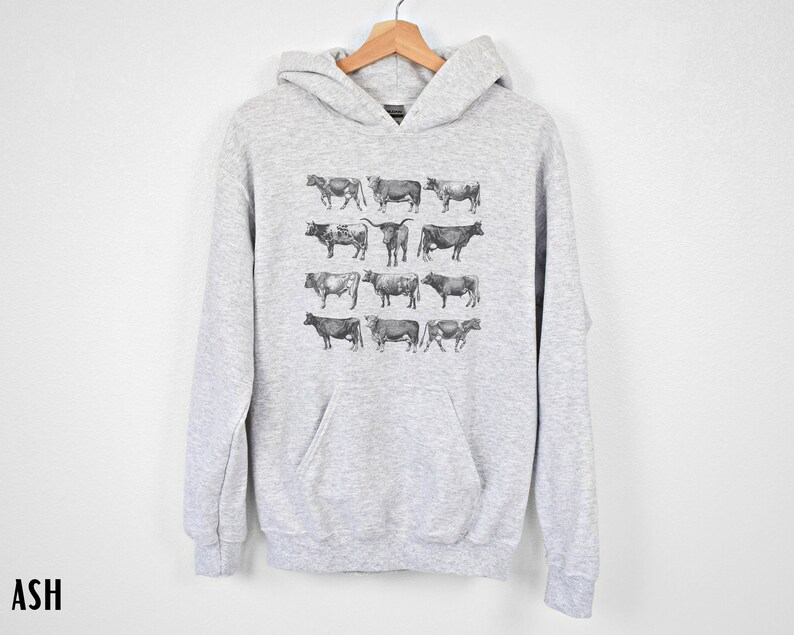 May include: A gray hooded sweatshirt with a print of various black and white cow illustrations.