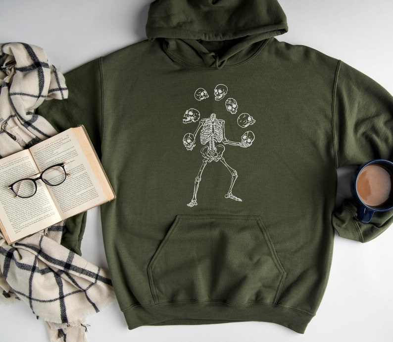 May include: A dark green hooded sweatshirt with a white graphic of a skeleton juggling skulls.