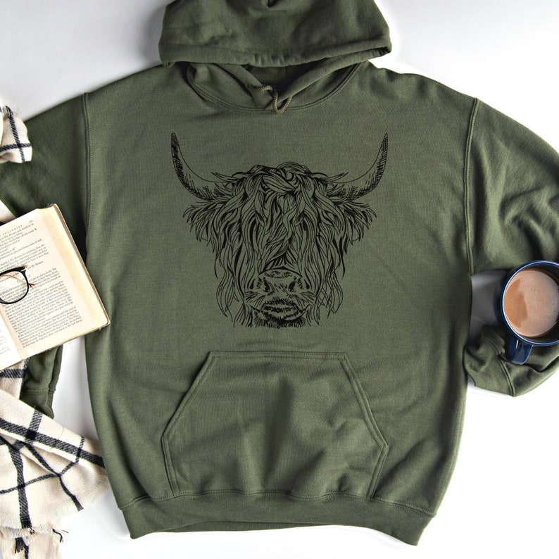 May include: A green hooded sweatshirt with a black graphic of a Highland cow's head.