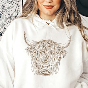 May include: A white hoodie with a brown line drawing of a Highland cow with long, shaggy hair and horns.