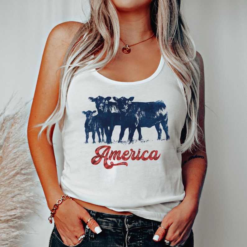 May include: White tank top with a graphic of three black cows and the word "America" in red and blue lettering.