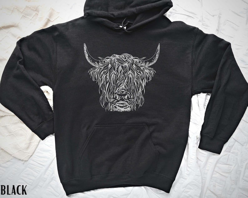 May include: Black hooded sweatshirt with a white graphic print of a Highland cow's head.