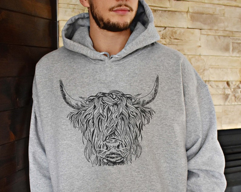 May include: A gray hooded sweatshirt with a black and white illustration of a Highland cow on the front.
