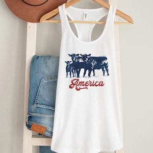 May include: White tank top with a blue and red graphic of four cows and the text "America".