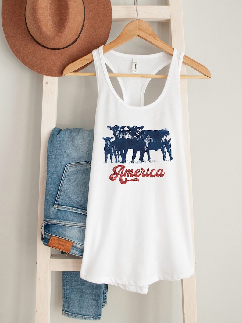 May include: White tank top with a blue and red graphic of four cows and the text "America".