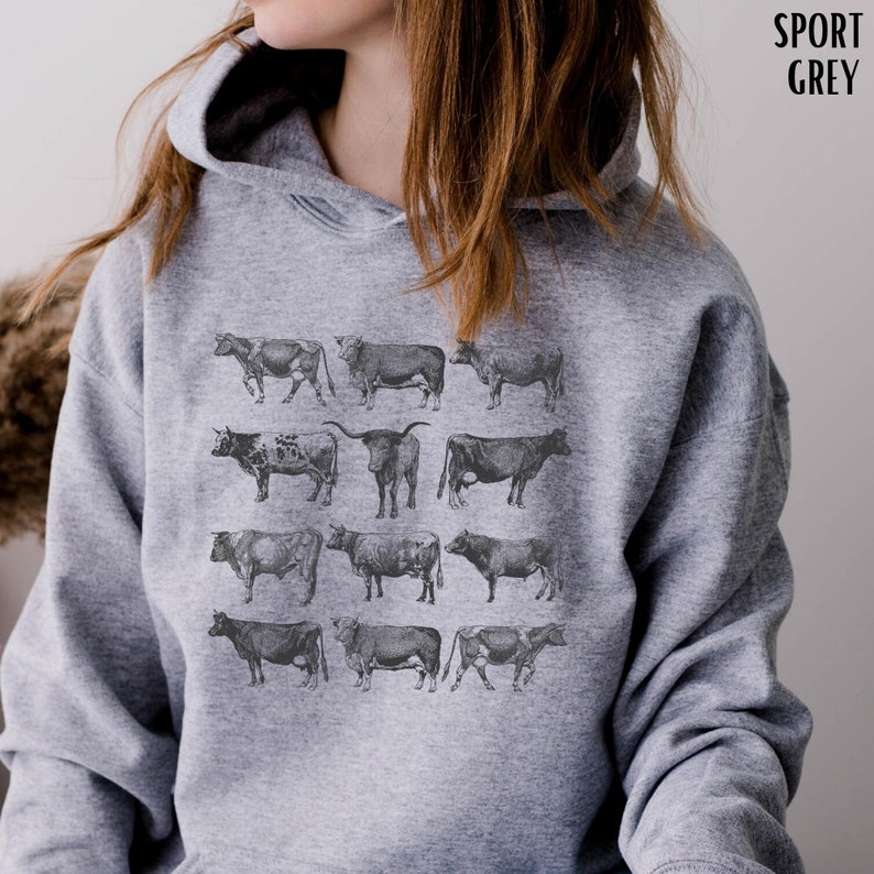 May include: A gray hooded sweatshirt with a print of 12 different cow illustrations. The cows are all in black and white and are arranged in a grid pattern.