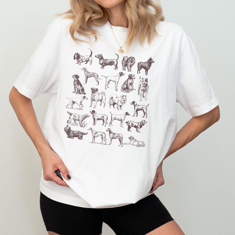 May include: White t-shirt with a graphic print of various dog breeds in black and white.