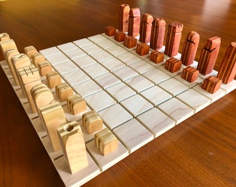 May include: A wooden chess set with light brown and reddish brown pieces on a light brown board. The pieces are stacked in rows on the board, with the pawns in the front and the rooks in the back.