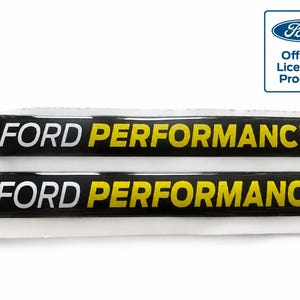 Op de afbeelding: Twee rechthoekige zwarte stickers met de tekst FORD PERFORMANCE in witte en gele letters. Het Ford-logo en de tekst Official Licensed Product zijn zichtbaar in de rechterbovenhoek van de afbeelding.