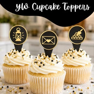 May include: Three cupcakes with white frosting and gold and black sprinkles. Each cupcake has a black and gold topper with a different design: a lantern, an envelope with a heart, and a brick wall with a trowel. The text "yw Cupcake Toppers" is above the cupcakes.