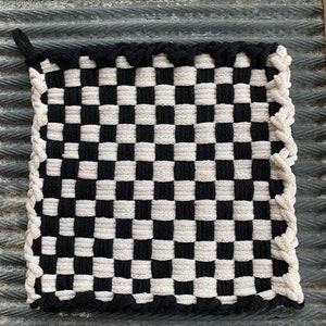 May include: Black and white checkered woven pot holder with a black fringe border.