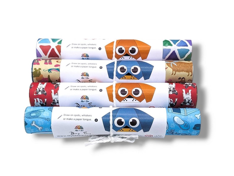Pode incluir: Cinco rolos de papel de embrulho coloridos com rostos de c&atilde;es e padr&otilde;es. Cada rolo tem um r&oacute;tulo branco com o texto "Desenhe manchas, bigodes ou fa&ccedil;a uma l&iacute;ngua de papel." e o logotipo "Dog Face by J & J".