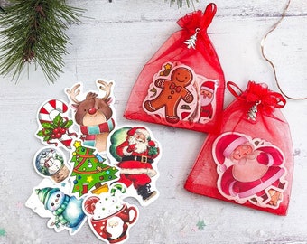 May include: Christmas-themed stickers and red mesh gift bags. Stickers include a gingerbread man, Santa Claus, reindeer, snowman, Christmas tree, and a snow globe. The bags are tied with red ribbons and have silver charms.
