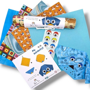 Pode incluir: Um conjunto de papel de origami e instru&ccedil;&otilde;es para fazer um projeto de origami com tema de c&atilde;es. O conjunto inclui papel estampado em azul, verde e laranja, olhos saltitantes e uma folha de instru&ccedil;&otilde;es com o texto "Oh, Biscuits!" e uma ilustra&ccedil;&atilde;o de um c&atilde;o.