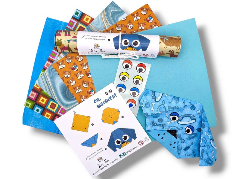 Pode incluir: Um conjunto de papel de origami e instru&ccedil;&otilde;es para fazer um projeto de origami com tema de c&atilde;es. O conjunto inclui papel estampado em azul, verde e laranja, olhos saltitantes e uma folha de instru&ccedil;&otilde;es com o texto "Oh, Biscuits!" e uma ilustra&ccedil;&atilde;o de um c&atilde;o.