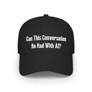 May include: Black baseball cap with the white text: "Can This Conversation Be Had With AI?" The cap has a curved brim and a rounded crown. The text is centered on the front of the cap.