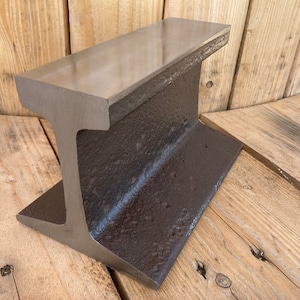 May include: A heavy-duty steel anvil with a flat top and a rounded base. The anvil is made of dark gray metal and has a rough, textured surface.