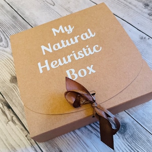 May include: A brown cardboard box with a brown ribbon tied around it. The box has white text that reads "My Natural Heuristic Box".