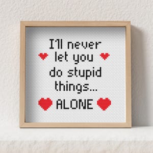以下が含まれることがあります： 「I'll never let you do stupid things... ALONE」というテキストが黒い文字で書かれた、額入りのクロスステッチアート。赤いハートのシンボルがテキストの周りに配置されています。アートワークは、明るい茶色の木製フレームに入っています。