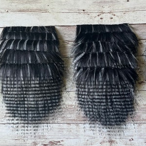 May include: Four black and white faux fur strips. The fur is long and fluffy with a gradient from black to white.