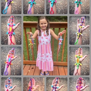 May include: A collection of colorful beaded lizard bracelets. Each bracelet features a different color combination and design. The bracelets are made with small, colorful beads and are strung on a string. The bracelets are shown being worn by a young girl.