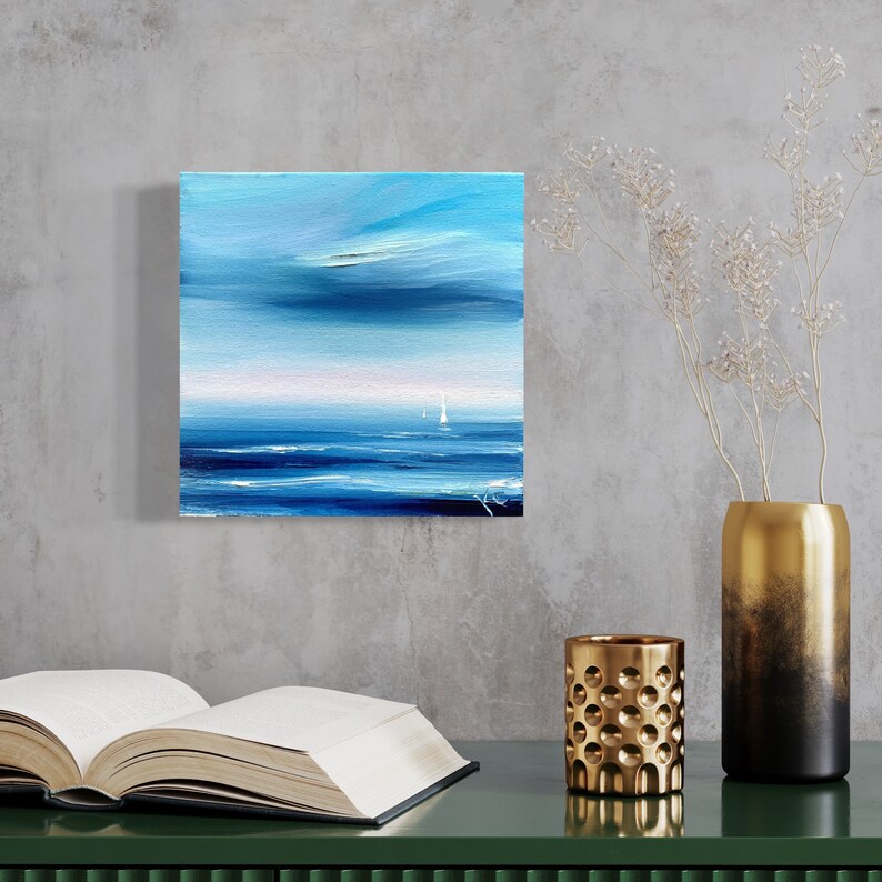 Op de afbeelding: Abstracte schilderij van een zeelandschap in blauwe en witte tinten. Het schilderij toont een rustige zee met een paar witte zeilboten in de verte. De lucht is lichtblauw met witte wolken.