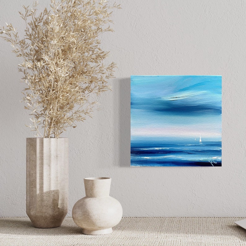 Op de afbeelding: Abstracte schilderij van een zeelandschap met een blauwe lucht en zee. Het schilderij toont witte zeilboten in de verte en een lichtblauwe lucht met witte wolken.