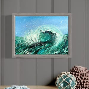 May include: A framed painting of a large, green wave crashing in the ocean. The wave is painted with a textured, brushstroke style. The painting is framed in a light gray wood frame.
