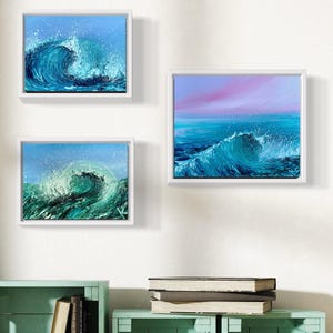 May include: Three framed paintings of ocean waves. The top painting shows a blue sky with a wave cresting. The middle painting shows a pink and purple sky with a wave cresting. The bottom painting shows a blue sky with a wave cresting.