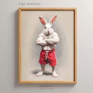 Könnte beinhalten: Gerahmter Druck eines muskulösen weißen Kaninchens in roten Shorts, die Arme verschränkt. Das Kunstwerk ist mit "hoher Auflösung" und "JERDELA PRINT STUDIO" gekennzeichnet. Das Kaninchen hat eine selbstbewusste Haltung.