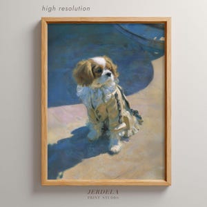 May include: A framed print of a Cavalier King Charles Spaniel wearing a vintage outfit. The dog is tan, white, and brown, with a light-colored coat and a ruffled collar. The print is labeled "high resolution" and "JERDELA PRINT STUDIO".