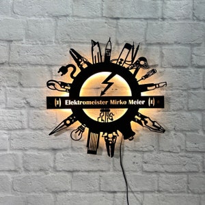 Peut inclure: Panneau métallique noir avec un design circulaire orné d'outils d'électricien entourant un éclair central. Le panneau porte l'inscription "Elektromeister Mirko Meier" et est éclairé d'une lumière chaude, idéal pour un atelier ou un bureau.