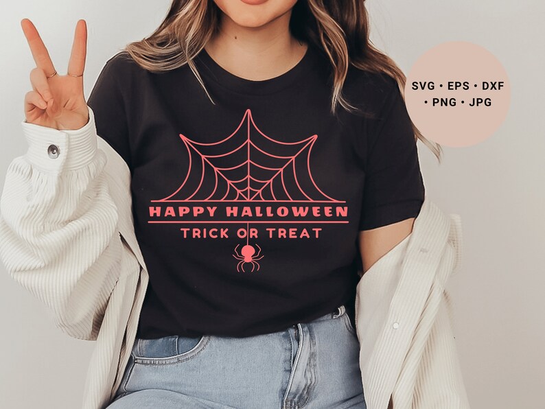 K&ouml;nnte beinhalten: Ein schwarzes T-Shirt mit einem pinkfarbenen Spinnennetz-Design und dem Text "Happy Halloween Trick or Treat".