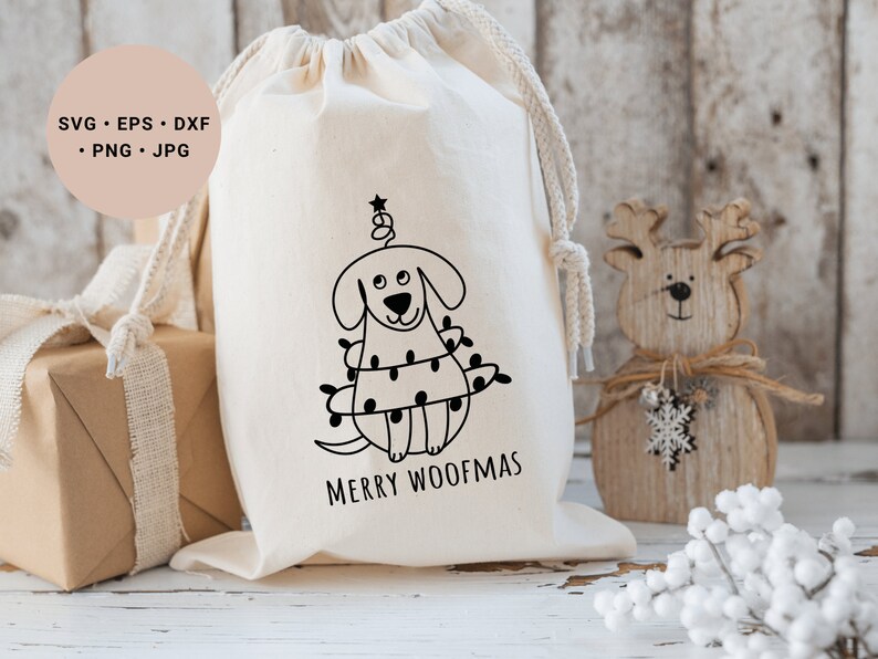 May include: A white canvas bag with a black and white illustration of a dog dressed as a Christmas tree. The text "Merry Woofmas" is printed below the illustration.