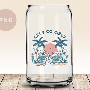 K&ouml;nnte beinhalten: Klares Trinkglas in Dosenform mit Strandmotiv. Das Design umfasst Palmen, einen Sonnenuntergang und den Text "LET'S GO GIRLS". Das Glas steht auf einer Holzoberfl&auml;che.