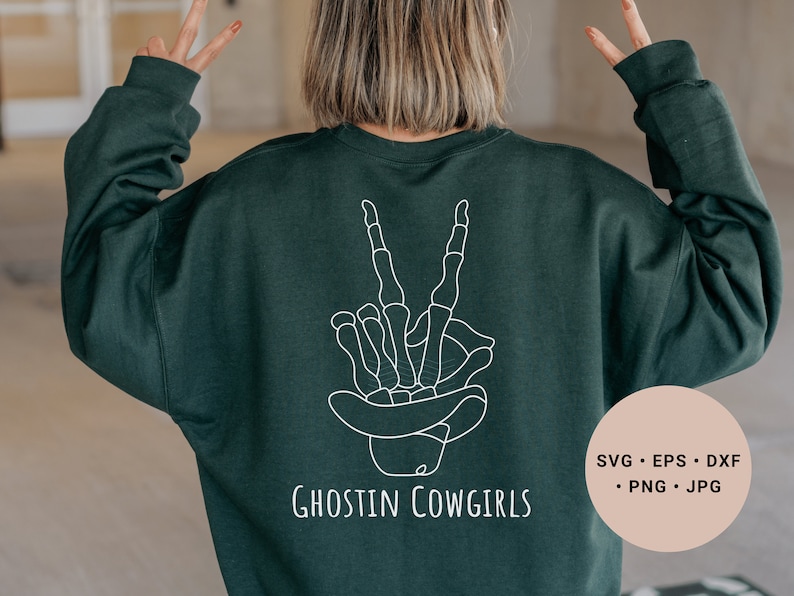 May include: A dark green sweatshirt with a white outline of a skeleton hand making a peace sign and the text "Ghostin Cowgirls".