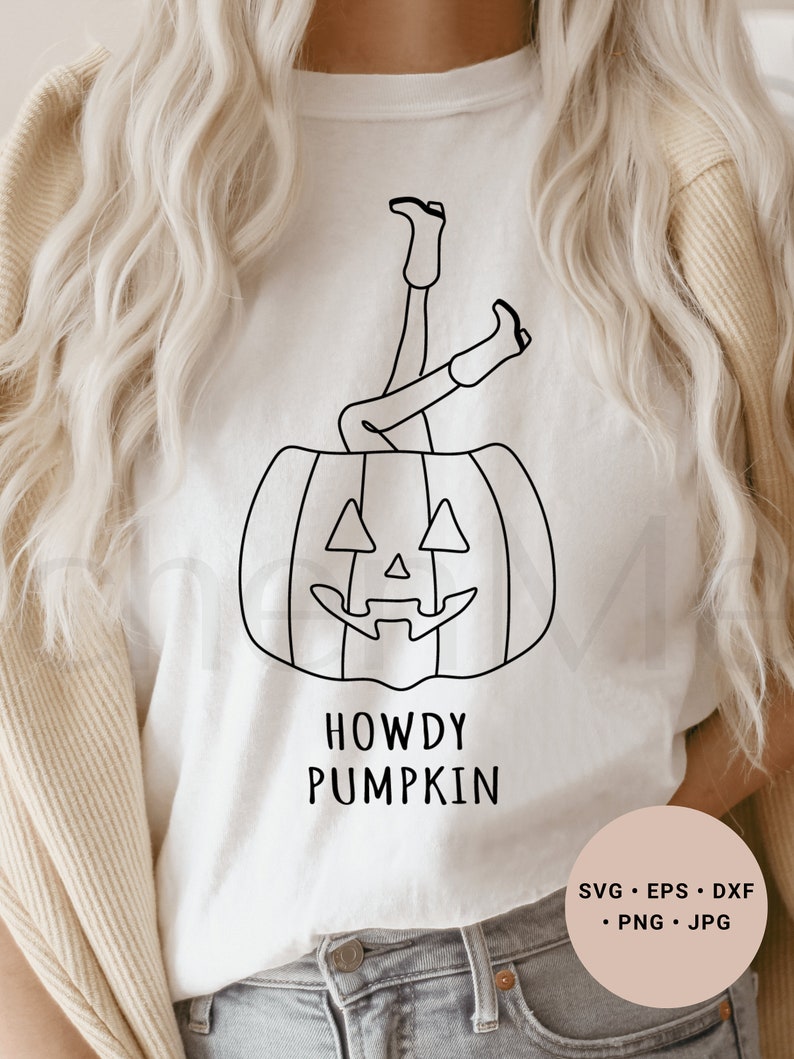 May include: A white t-shirt with a black line drawing of a person's legs sticking out of a pumpkin. The text "Howdy Pumpkin" is below the pumpkin.