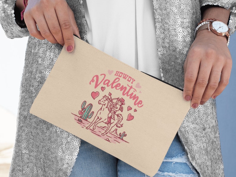 May include: A beige canvas zippered pouch with a pink and white illustration of a cowboy riding a horse with the text "Howdy Valentine" and pink hearts.