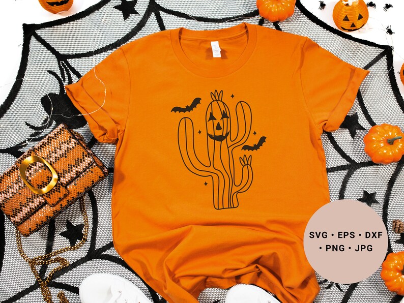 May include: Orange t-shirt featuring a black graphic of a cactus with a jack-o'-lantern face. The cactus is surrounded by bats and stars. The text "SVG - EPS - DXF - PNG - JPG" is in the bottom right corner of the image.